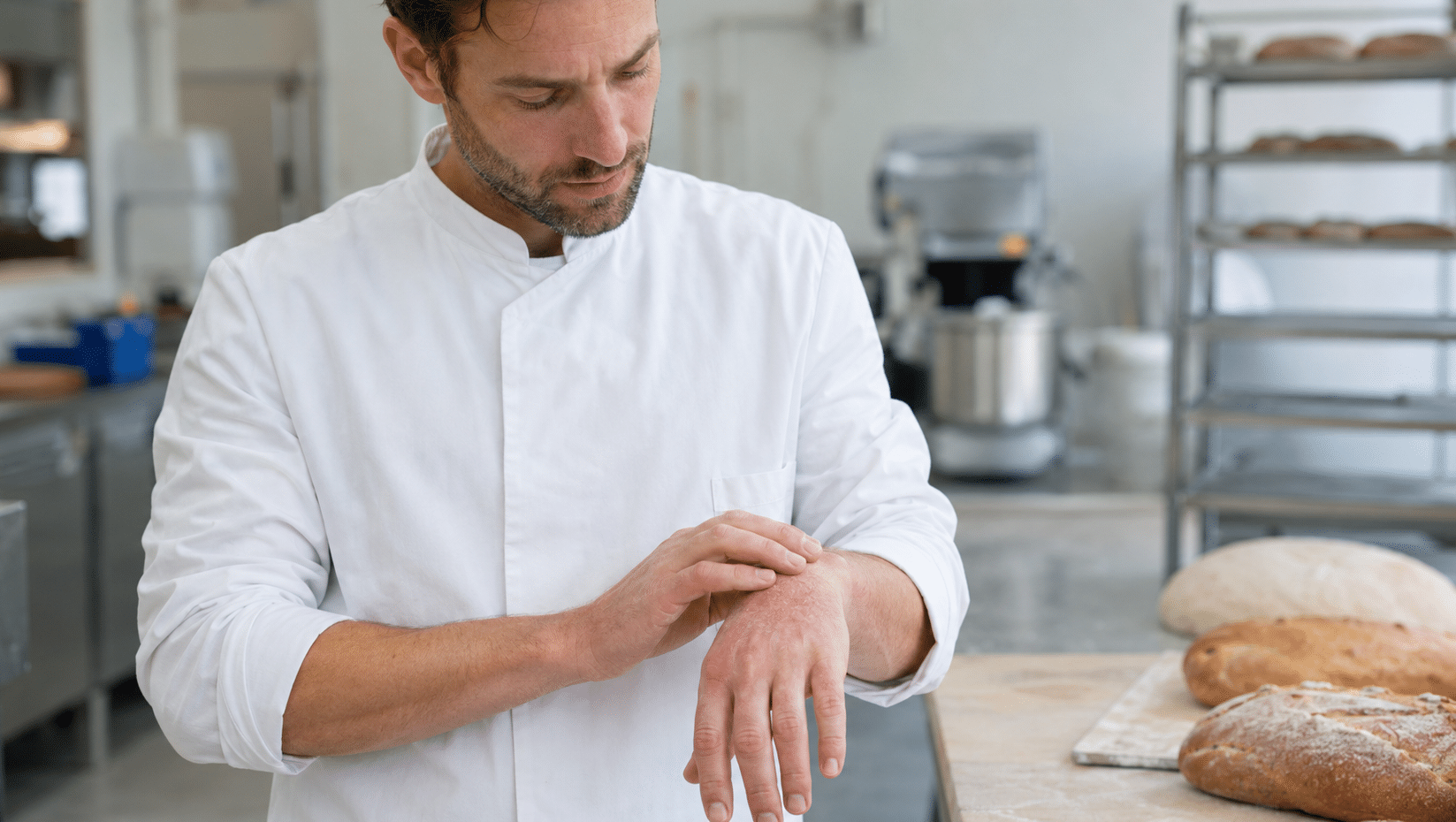 Bakker bekijkt mild handeczeem aan zijn handen in een professionele bakkerij