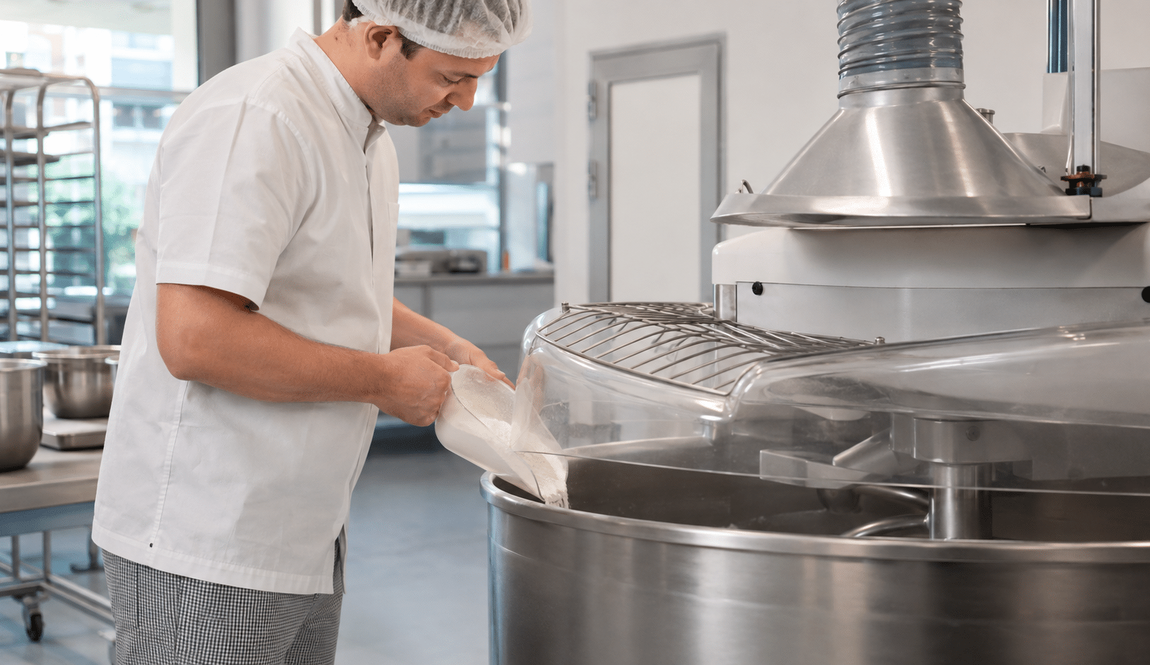 Bakker verwerkt meel vanaf geringe hoogte in een afgedekte menginstallatie